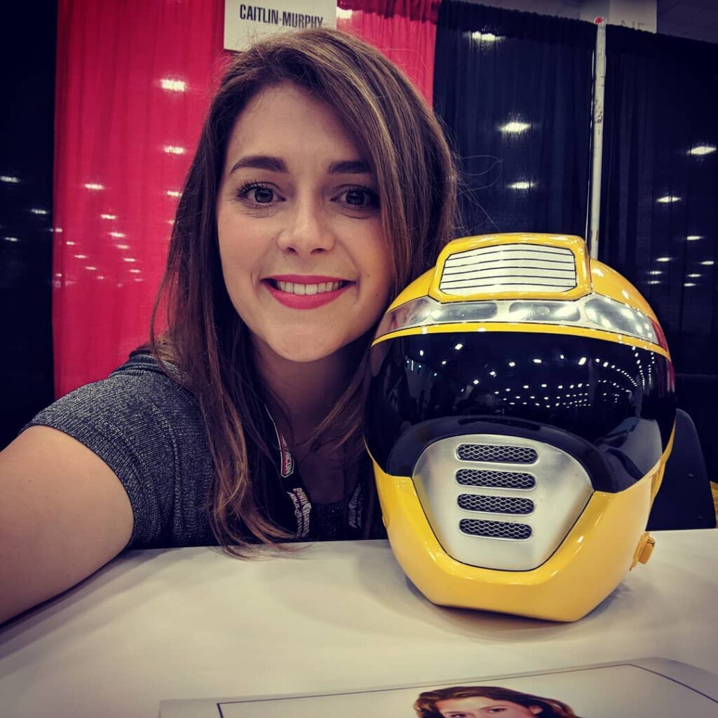 Caitlin Murphy with yellow ranger helmet sitting on a chair